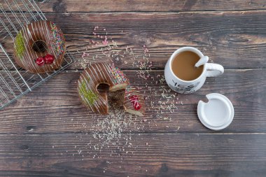 Tahta bir masanın üzerinde bir bardak içkiyle çikolatalı çörek kırdım. Yüksek kalite fotoğraf