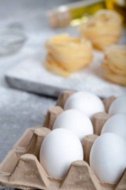 Çiğ tagliatelle, siyah yüzeyde un, yağ ve çiğ yumurta ile yuva yapar. Yüksek kalite fotoğraf