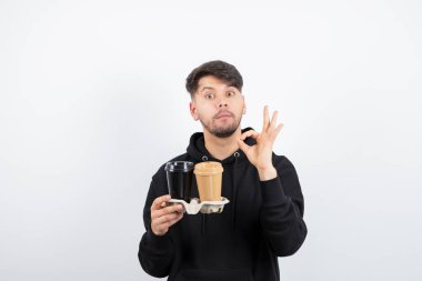 Çekici bir adamın portresi bir karton kutuda iki paket kahve tutuyor. Yüksek kalite fotoğraf