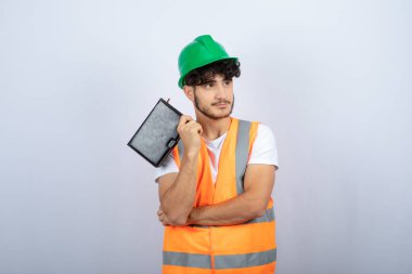 Yeşil şapkalı genç mühendis elinde siyah defter ve ayakta duruyor. Yüksek kalite fotoğraf