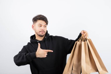 Siyah kapüşonlu yakışıklı adamın bir sürü el çantası taşıdığı fotoğraf. Yüksek kalite fotoğraf