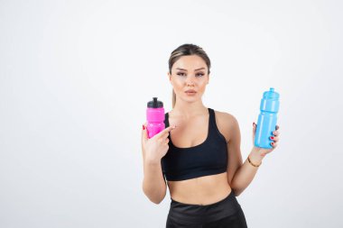 Mavi ve pembe su şişeleri tutan genç atletik kadın portresi. Yüksek kalite fotoğraf