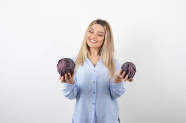 Mavi elbiseli güzel bir kadın beyaz arka planda mor lahana tutuyor. Yüksek kalite fotoğraf