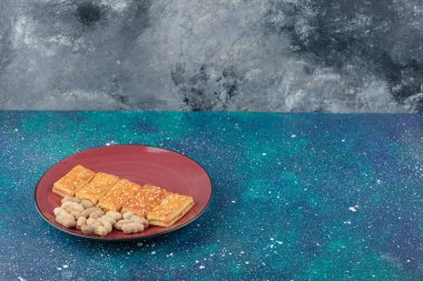 Sağlıklı fındıklı kırmızı bir tabak ve galaksi arka planında lezzetli krakerler. Yüksek kalite fotoğraf