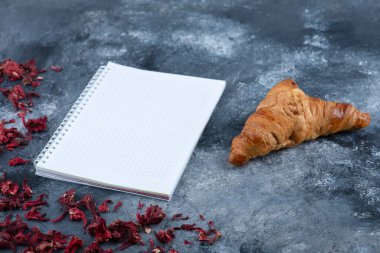 Taze ve lezzetli kruvasan ve açık bir defter. Yüksek kalite fotoğraf