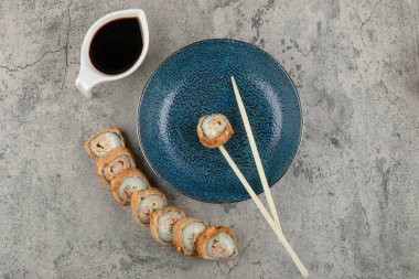 Mavi tabak, sıcak suşi ruloları ve taş yüzeyde soya sosu. Yüksek kalite fotoğraf