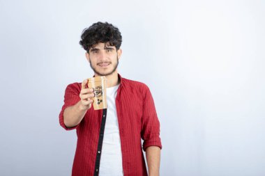 Beyaz duvarda mola vermek için elinde kahve tutan esmer adamın fotoğrafı. Yüksek kalite fotoğraf