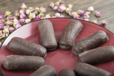 Tatlı çikolatalı kekler ve ahşap arka planda güller olan kırmızı tabak. Yüksek kalite fotoğraf