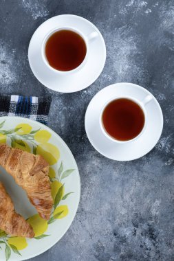 Taze ve lezzetli kruvasanlar ve iki fincan sıcak çay. Yüksek kalite fotoğraf