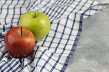 Çizgili masa örtüsüne yerleştirilmiş lezzetli yeşil ve kırmızı taze elmalar. Yüksek kalite fotoğraf
