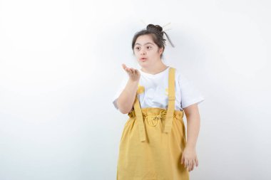 Genç ve güzel kız model ayakta ve beyaz duvara bir öpücük konduruyor. Yüksek kalite fotoğraf