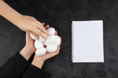 El, siyah arka plandaki kadın ellerinden çiğ beyaz yumurta alıyor. Yüksek kalite fotoğraf