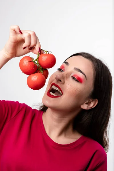 Mooi Meisje Probeert Rode Tomaten Tegen Een Witte Muur Bijten — Stockfoto