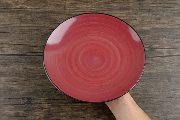 Κάτοψη Του Ανθρώπου Χέρι Κρατώντας Ένα Άδειο Κόκκινο Πιάτο Ένα — Φωτογραφία Αρχείου