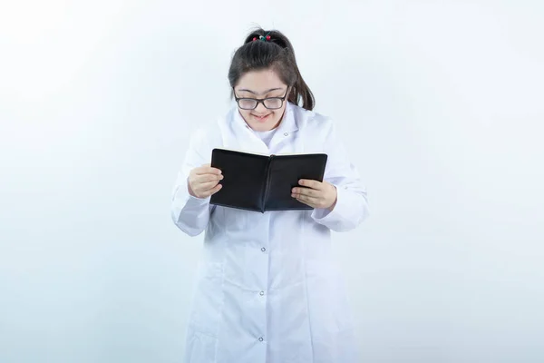 医師の制服を着た若い女性の女の子が立ってメモ帳を開いて保持します 高品質の写真 — ストック写真