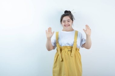 Beyaz duvara karşı duran ve poz veren genç, güzel bir kız. Yüksek kalite fotoğraf