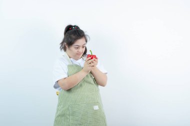 Kareli önlük giymiş genç ve güzel bir kız kırmızı dolmalık bibere bakıyor. Yüksek kalite fotoğraf