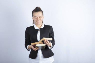 Beyaz arka planda bir sürü kitapla poz veren genç bir kızın portresi. Yüksek kalite fotoğraf