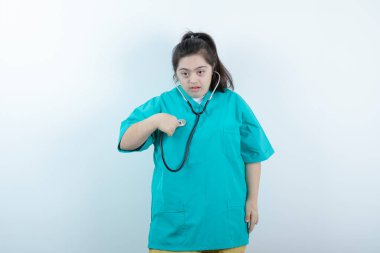 Beyaz duvarda steteskopla duran genç bayan hemşire. Yüksek kalite fotoğraf