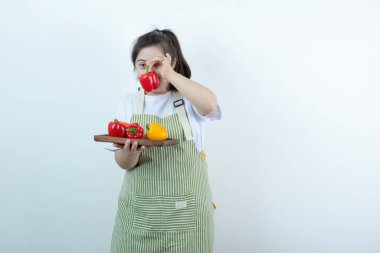 Önlüklü genç bir kız elinde taze sebzelerle tahta bir tahta tutuyor. Yüksek kalite fotoğraf