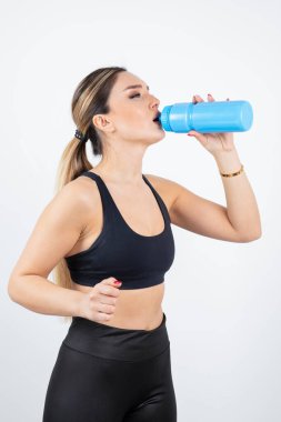 Mavi bir şişe su içen genç atletik kadın portresi. Yüksek kalite fotoğraf
