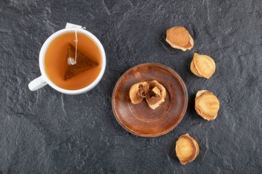 Siyah arka planda bir fincan çayla ceviz şeklinde lezzetli kurabiyeler. Yüksek kalite fotoğraf