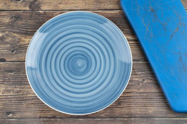 Empty blue dinner plate and blue board on wooden background. High quality photo
