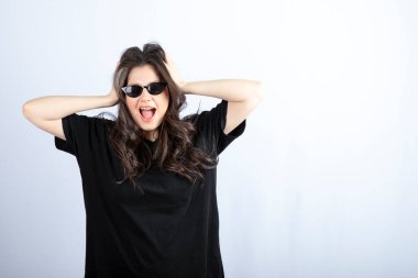 Beyaz arka planda güneş gözlüğüyle poz veren şık bir genç kadın. - Evet. Yüksek kalite fotoğraf