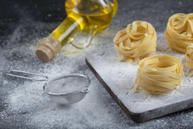 Tahta ahşap tagliatelle tahtasının üzerinde un ve zeytinyağı olan yuvaları var. Yüksek kalite fotoğraf