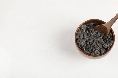 Ahşap kase dolusu ayçiçeği siyah tohumlar beyaz arka plana yerleştirilmiş. Yüksek kalite fotoğraf