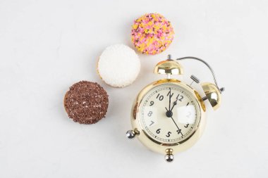 Süslü kremalı kurabiye çeşitleri ve beyaz arka planda bir saat. Yüksek kalite fotoğraf