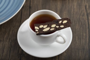 Tahta masaya dilimlenmiş kek konulmuş beyaz bir fincan sıcak çay. Yüksek kalite fotoğraf