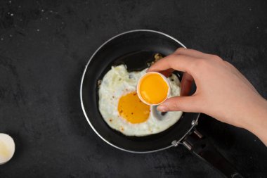 Siyah yüzeyde kırık yumurtayı tutan kadın eli. Yüksek kalite fotoğraf