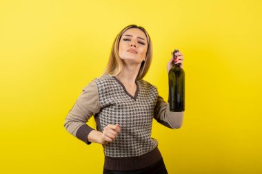 Elinde şarap şişesi olan ve ayakta duran genç bir kadın resmi. Yüksek kalite fotoğraf