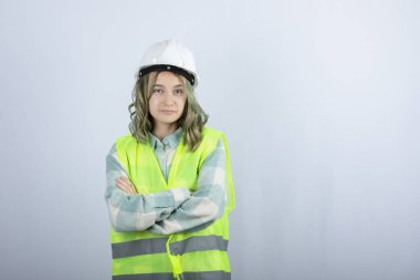 Beyaz fonda duran beyaz şapkalı genç inşaat işçisinin görüntüsü. Yüksek kalite fotoğraf