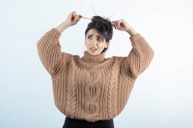 Saçlarını kalemle ören örgü elbiseli güzel bir kadının portresi. Yüksek kalite fotoğraf