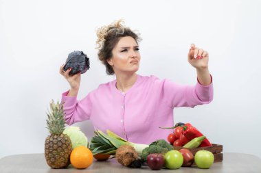 Masada elinde mor lahanayla oturan güzel bir ev hanımı resmi. Yüksek kalite fotoğraf