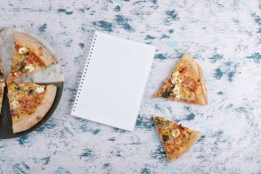 Mermer zemin üzerinde defter olan sıcak pizza dilimleri. Yüksek kalite fotoğraf