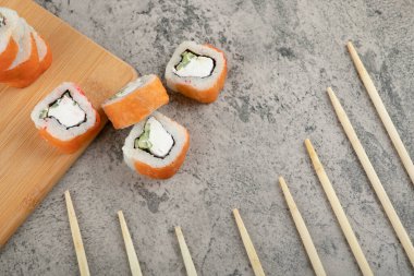 Taş zeminde taze somonla süslenmiş lezzetli suşi ruloları. Yüksek kalite fotoğraf