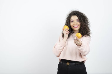 Portakal tutan pembe kazaklı genç kıvırcık kadın portresi. Yüksek kalite fotoğraf