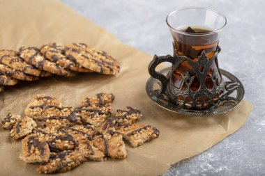 Yulaf ezmeli kurabiyeli bir bardak çay yağsız bir kağıda konur. Yüksek kalite fotoğraf