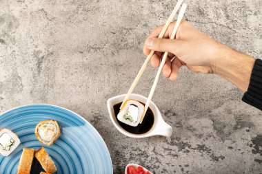 Taştan arka planda yemek çubukları olan suşi rulosunu ele alalım. Yüksek kalite fotoğraf