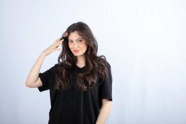 Beyaz arka planda fırçayla poz veren genç ve güzel bir model resmi. Yüksek kalite fotoğraf