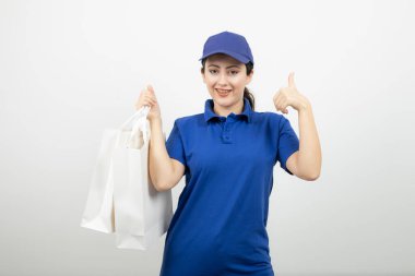 Mavi elbiseli, beyaz çantalı güzel bir kadın kurye başparmak işareti yapıyor. Yüksek kalite fotoğraf