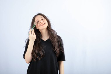 Beyaz arka planda fırçayla gölge uygulayan genç ve güzel bir model resmi. Yüksek kalite fotoğraf