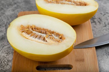 Tahta kesme tahtasına yarım dilimlenmiş sarı kavun yerleştirilmiş. Yüksek kalite fotoğraf