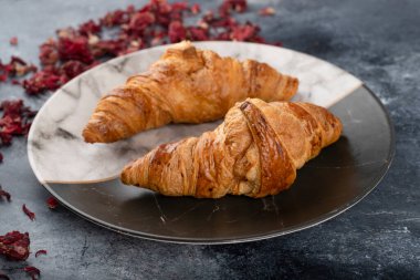 Güzel bir tabağa yerleştirilmiş lezzetli tereyağlı kruvasanlar. Yüksek kalite fotoğraf