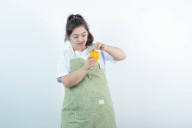 Kareli önlüğün içinde duran ve ellerinde sarı dolma biber tutan genç ve güzel bir kız. Yüksek kalite fotoğraf