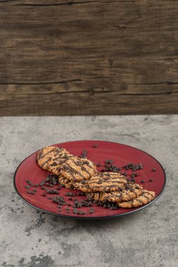 Kırmızı tabağa çikolata damlaları serpiştirilmiş lezzetli kurabiyeler. Yüksek kalite fotoğraf