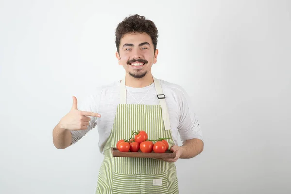 Jeune Homme Souriant Tenant Une Pile Tomates Biologiques Pointant Doigt — Photo